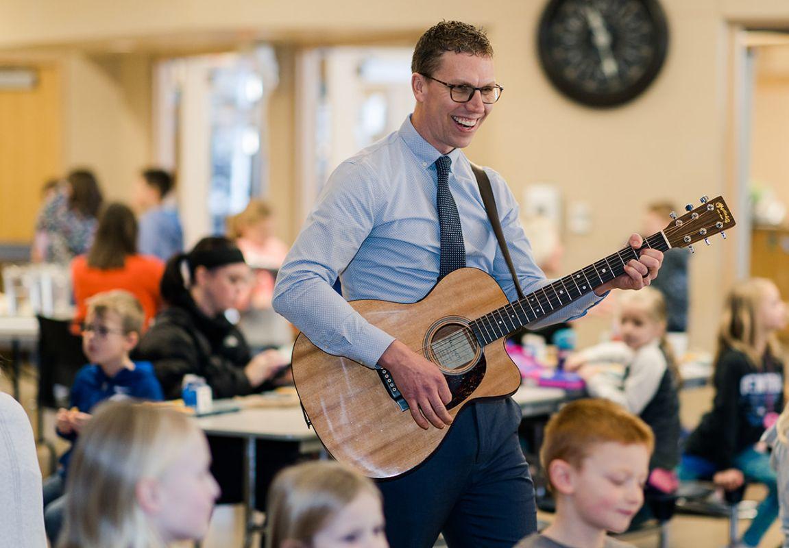Jon De Groot playing guitar for students